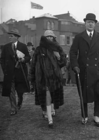 Gabrielle Chanel in a fur-collared coat and cloche hat, walking beside the Duke of Westminster at Aintree